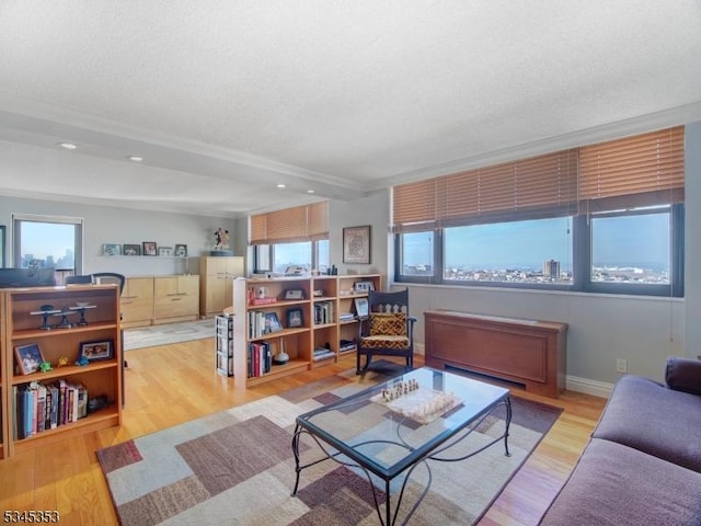 living area featuring beamed ceiling, wood finished floors, a wealth of natural light, and a textured ceiling
