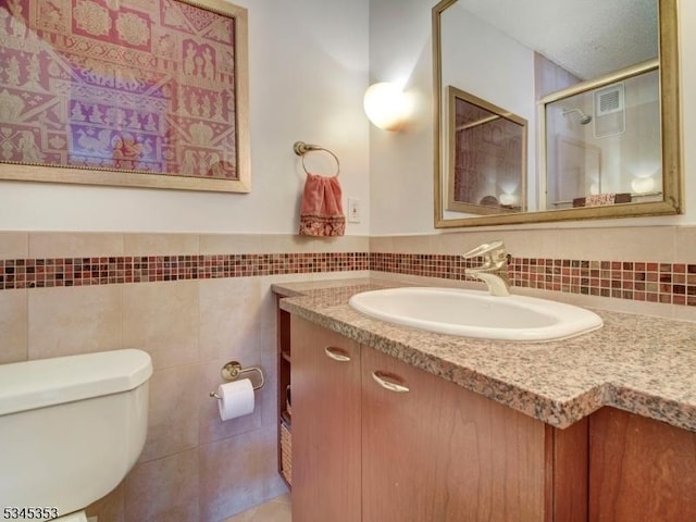 bathroom with vanity, visible vents, a shower stall, tile walls, and toilet
