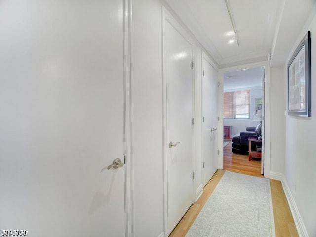 hall with baseboards and light wood finished floors
