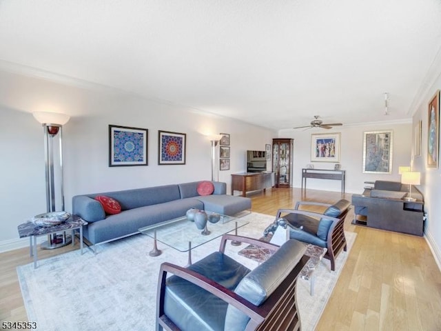 living room with light wood-style flooring, baseboards, crown molding, and ceiling fan