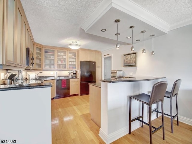 kitchen with light wood finished floors, dark countertops, dishwasher, and freestanding refrigerator
