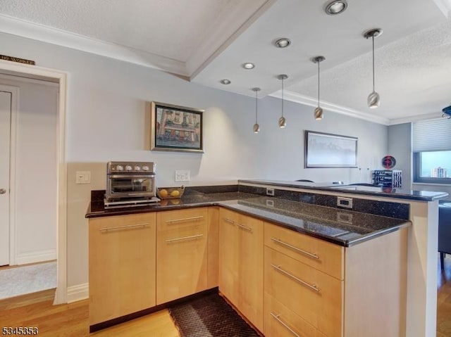 kitchen featuring dark stone counters, light wood-style floors, light brown cabinets, and ornamental molding