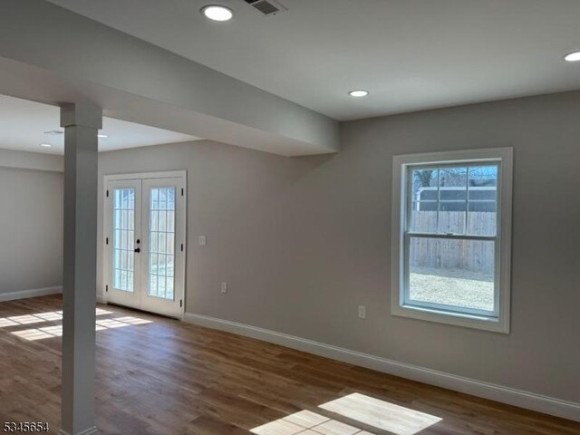 unfurnished room featuring baseboards, wood finished floors, and plenty of natural light