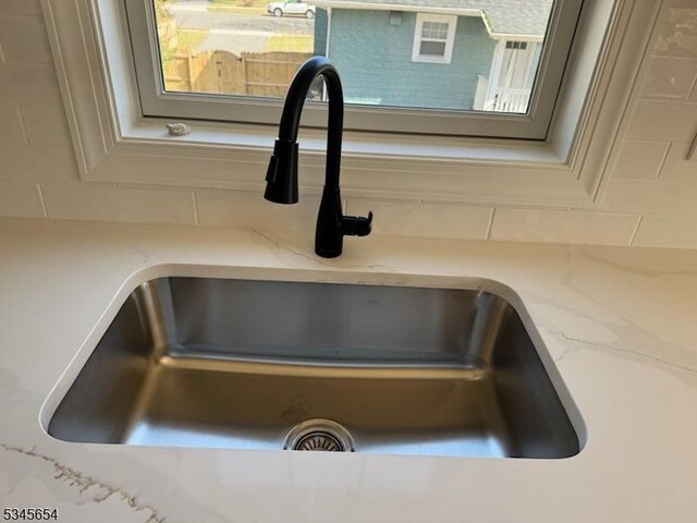 interior details featuring a sink and light stone countertops