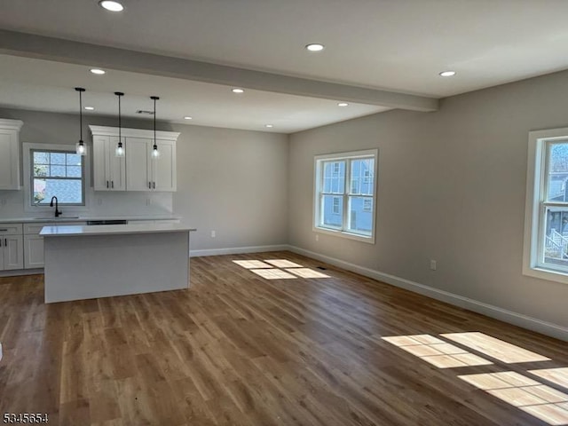 kitchen with baseboards, a sink, dark wood-type flooring, and beamed ceiling