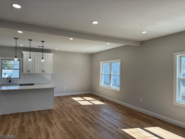 kitchen with baseboards, light countertops, beam ceiling, and dark wood-style flooring