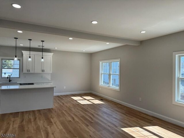 kitchen featuring light countertops, beam ceiling, baseboards, and dark wood-type flooring