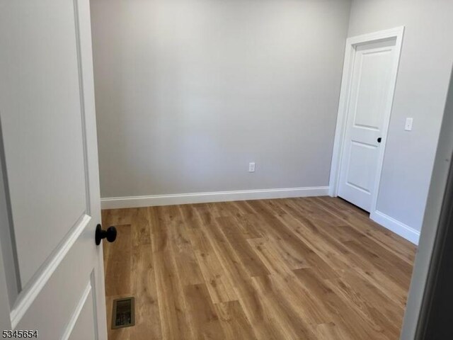 spare room featuring baseboards, visible vents, and light wood-style floors