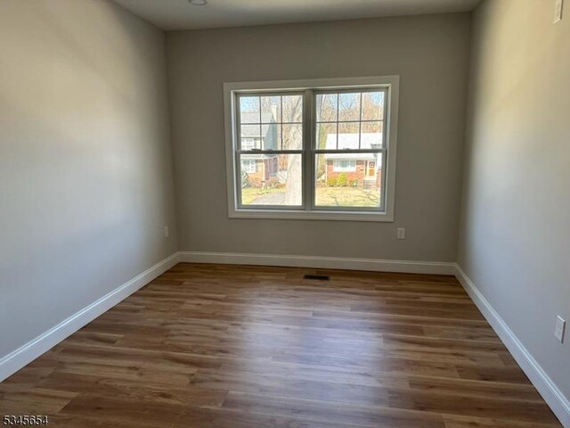 spare room with baseboards and wood finished floors