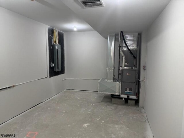finished basement featuring heating unit, visible vents, and electric panel