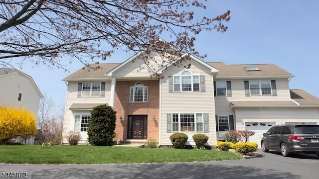 view of front of house featuring driveway, a front lawn, brick siding, and a garage