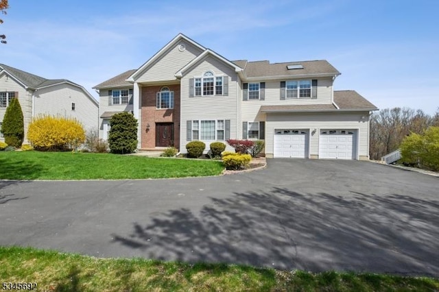 traditional home featuring aphalt driveway, a front lawn, and a garage