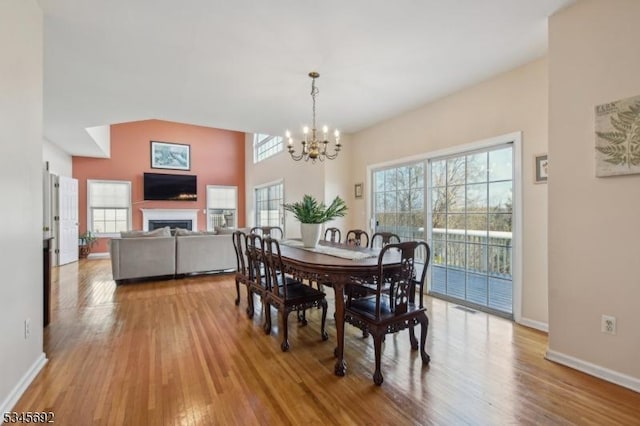 dining space with an inviting chandelier, wood finished floors, a fireplace, and baseboards
