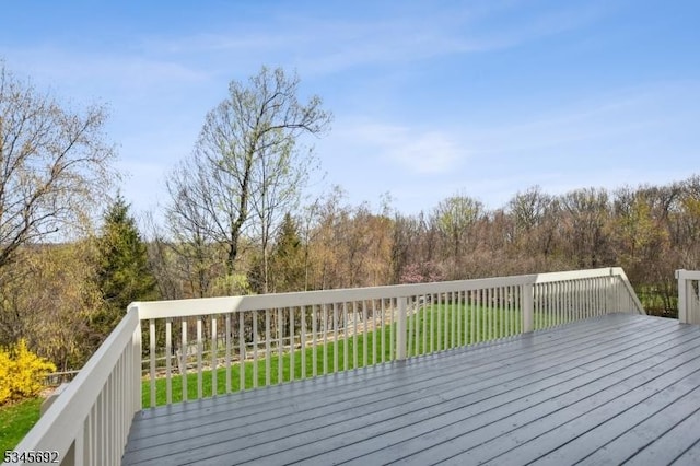 wooden terrace featuring a yard and a view of trees