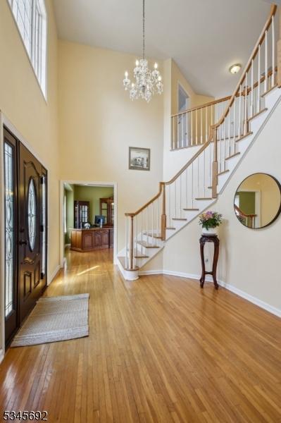 entryway with a high ceiling, stairway, a notable chandelier, baseboards, and wood finished floors
