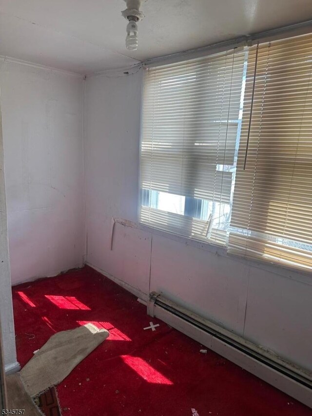 unfurnished room featuring a baseboard radiator and carpet flooring