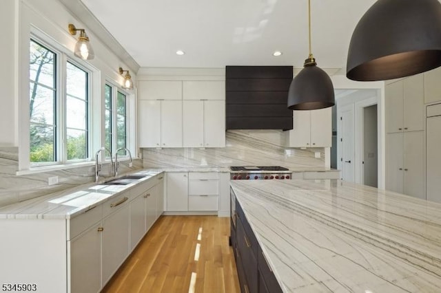 kitchen featuring backsplash, white cabinetry, a sink, and custom range hood