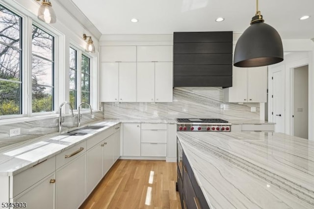 kitchen featuring a sink, white cabinets, light stone countertops, and wall chimney exhaust hood