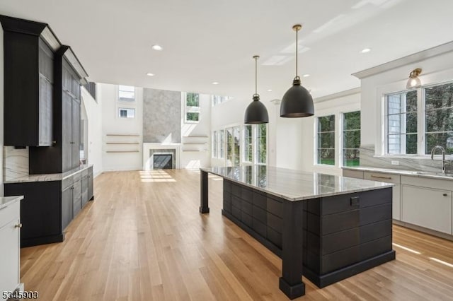 kitchen featuring decorative backsplash, recessed lighting, dark cabinetry, a sink, and light wood finished floors