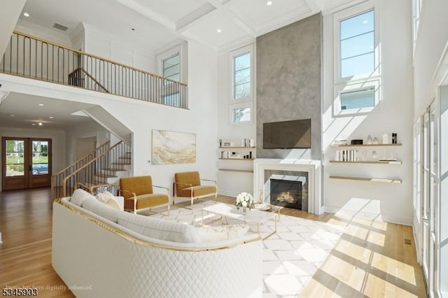 living room featuring stairs, a towering ceiling, and wood finished floors
