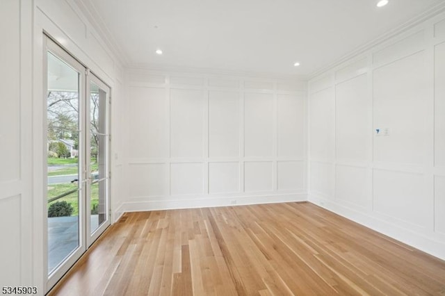 spare room featuring crown molding, recessed lighting, light wood finished floors, and a decorative wall