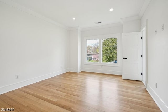 unfurnished room featuring crown molding, baseboards, light wood-style flooring, and visible vents