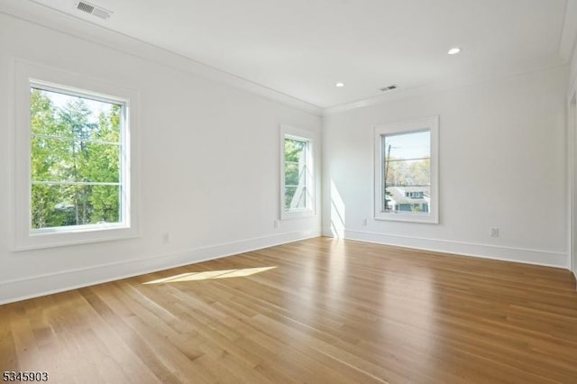 spare room with crown molding, baseboards, visible vents, and light wood finished floors