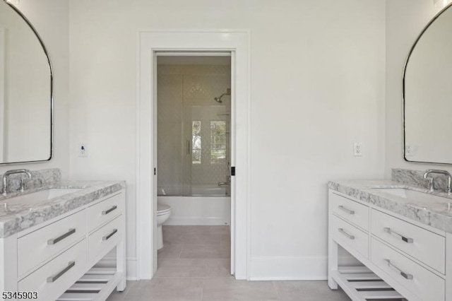 bathroom with a sink, tile patterned floors, toilet, and two vanities