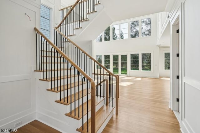stairs featuring french doors, a towering ceiling, and wood finished floors