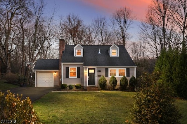 new england style home featuring a garage, asphalt driveway, a chimney, and a front lawn