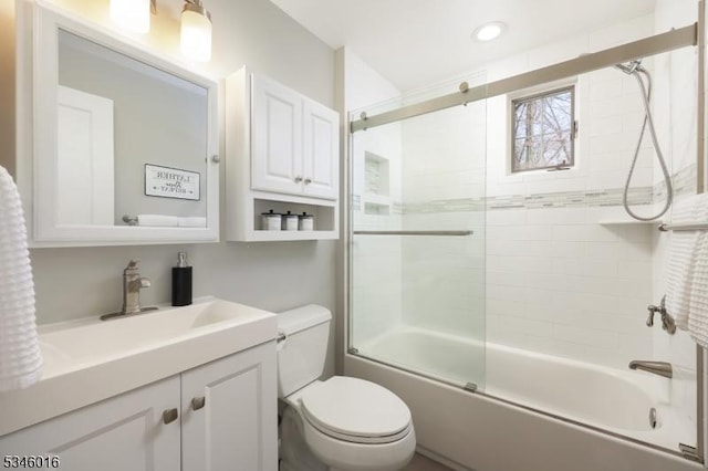 bathroom featuring toilet, vanity, combined bath / shower with glass door, and recessed lighting