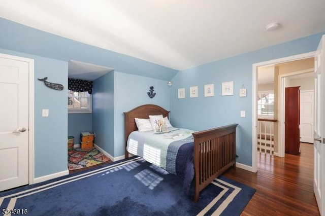 bedroom with baseboards, lofted ceiling, wood finished floors, and multiple windows