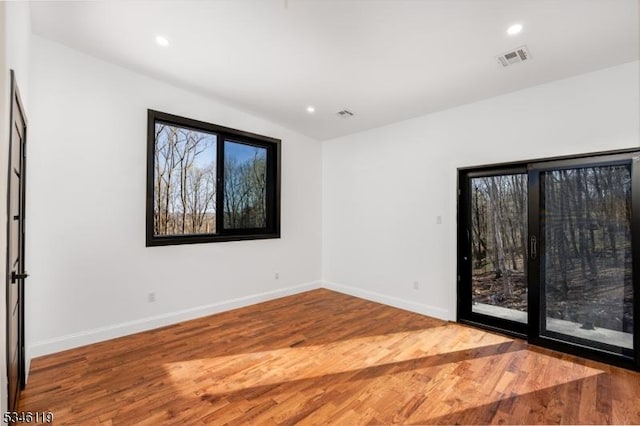 empty room featuring recessed lighting, wood finished floors, visible vents, and baseboards