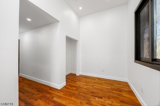 empty room with baseboards, wood finished floors, and recessed lighting