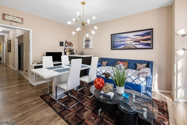 dining area featuring baseboards, wood finished floors, and an inviting chandelier