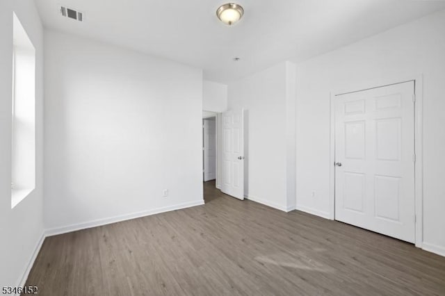 unfurnished bedroom with wood finished floors, baseboards, and visible vents