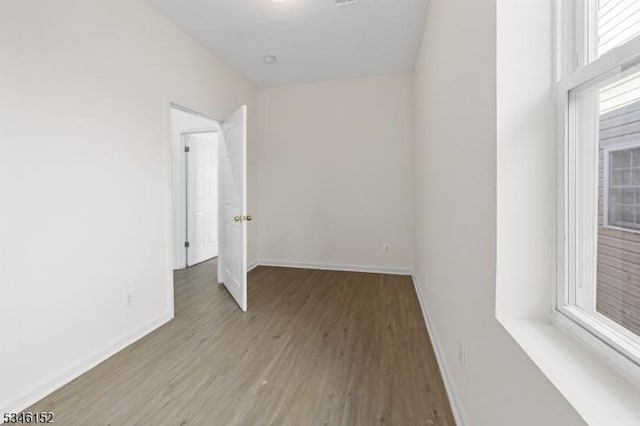 spare room with visible vents, baseboards, and wood finished floors