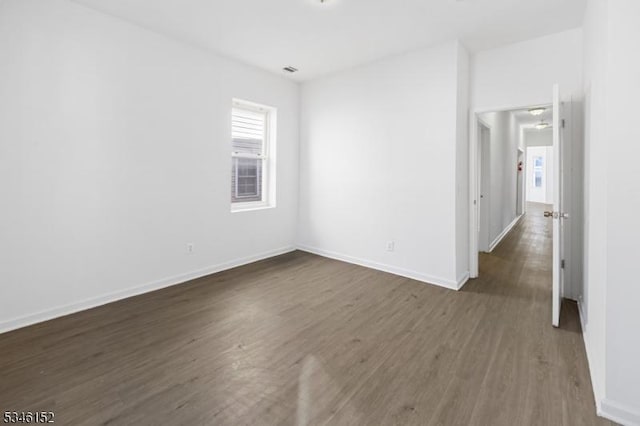 unfurnished room featuring baseboards and dark wood-type flooring