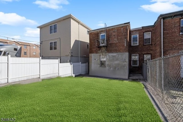 rear view of house with fence and a lawn