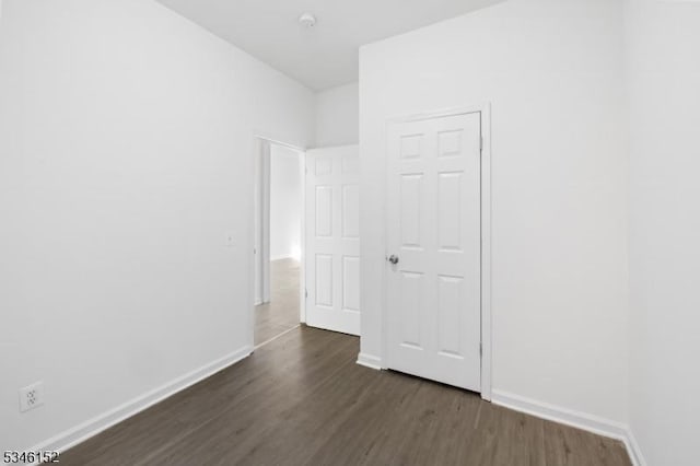 spare room featuring baseboards and dark wood-style flooring