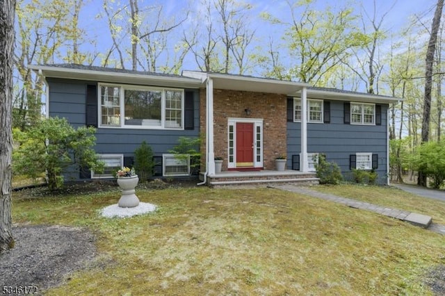 raised ranch featuring brick siding and a front lawn