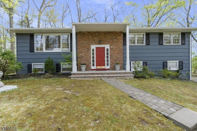 raised ranch featuring brick siding and a front yard