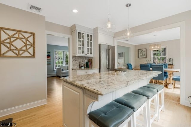 kitchen featuring a healthy amount of sunlight, light wood finished floors, and high quality fridge