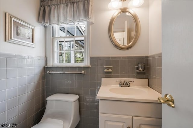 bathroom featuring toilet, tile walls, wainscoting, and vanity