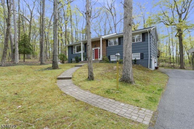 split foyer home with an attached garage, a front lawn, and driveway