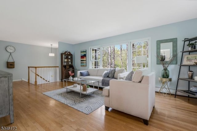 living area featuring baseboards, a baseboard radiator, and wood finished floors