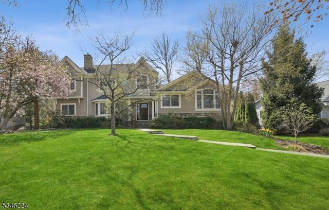 view of front of house featuring a front lawn, stone siding, and a chimney