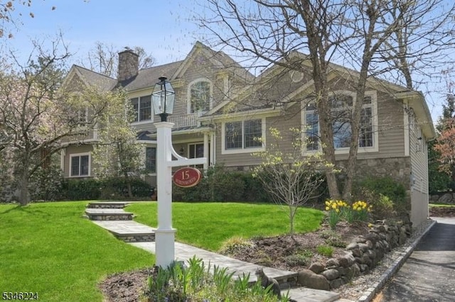 view of front of house featuring stone siding, a chimney, and a front yard