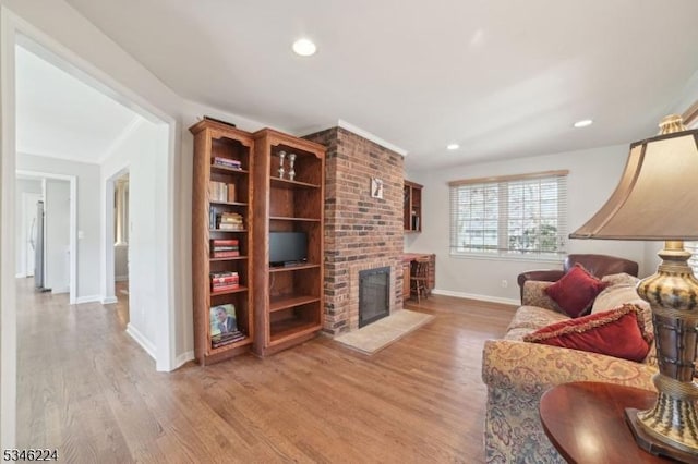 living area with baseboards, a fireplace, recessed lighting, and wood finished floors