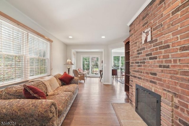 living area featuring brick wall, a fireplace, wood finished floors, baseboards, and recessed lighting